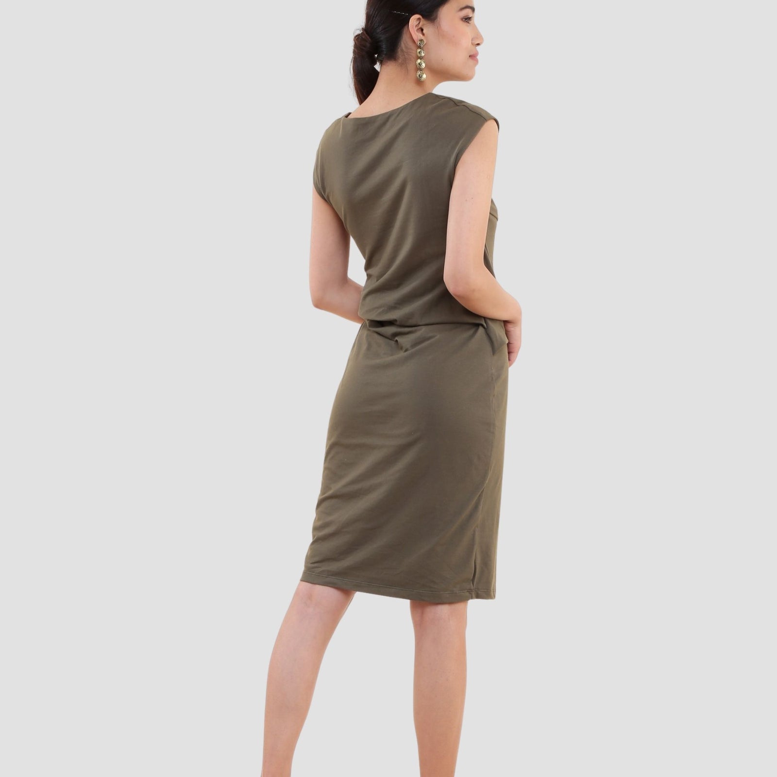Woman wearing olive green organic cotton t-shirt dress with cap sleeves and knee-length hem back view