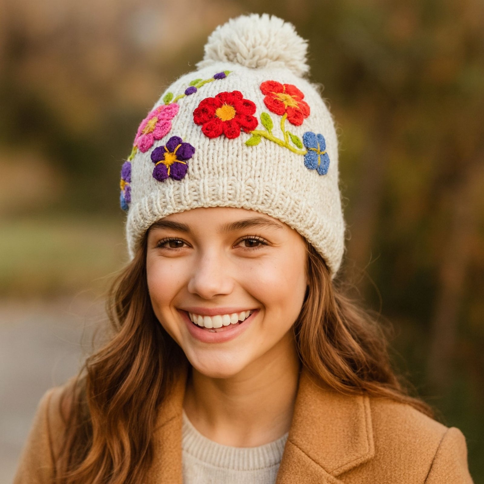 Cream hand knit wool beanie with colorful hand-embroidered flowers and large pom pom, fleece lined winter hat