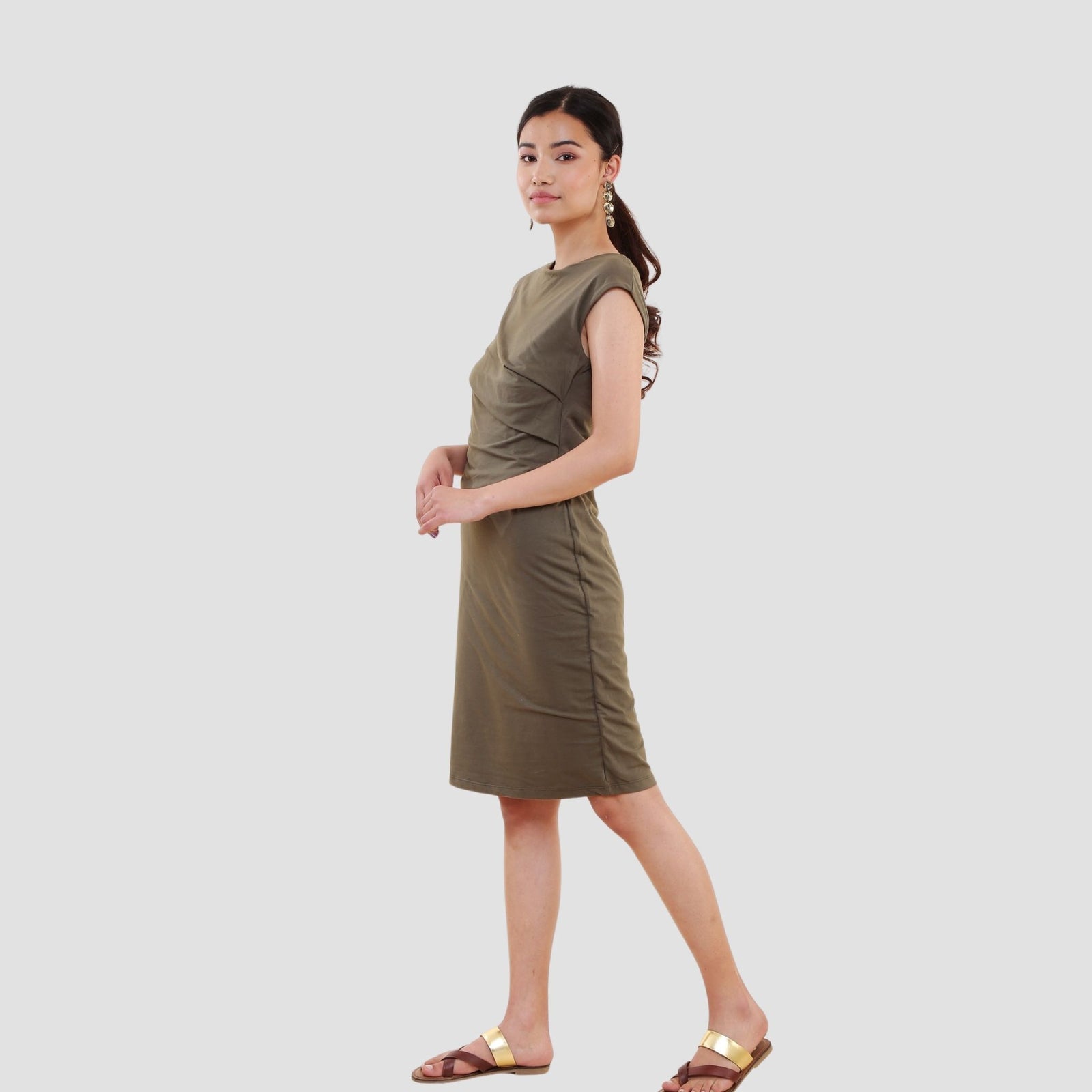 Woman wearing olive green organic cotton t-shirt dress with cap sleeves and knee-length hem on white background