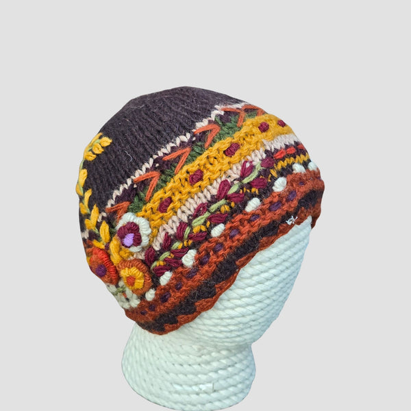 Deep plum hand knitted New Zealand wool beanie with floral embroidery and mustard crochet band fleece lined handmade in Nepal on mannequin head